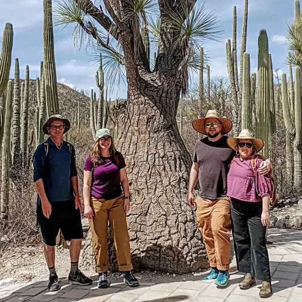 alt="Friends posing beside a centuries-old endemic cactus in the Cuicatlán–Tehuacán Biosphere Reserve, celebrating Mexico’s desert biodiversity.